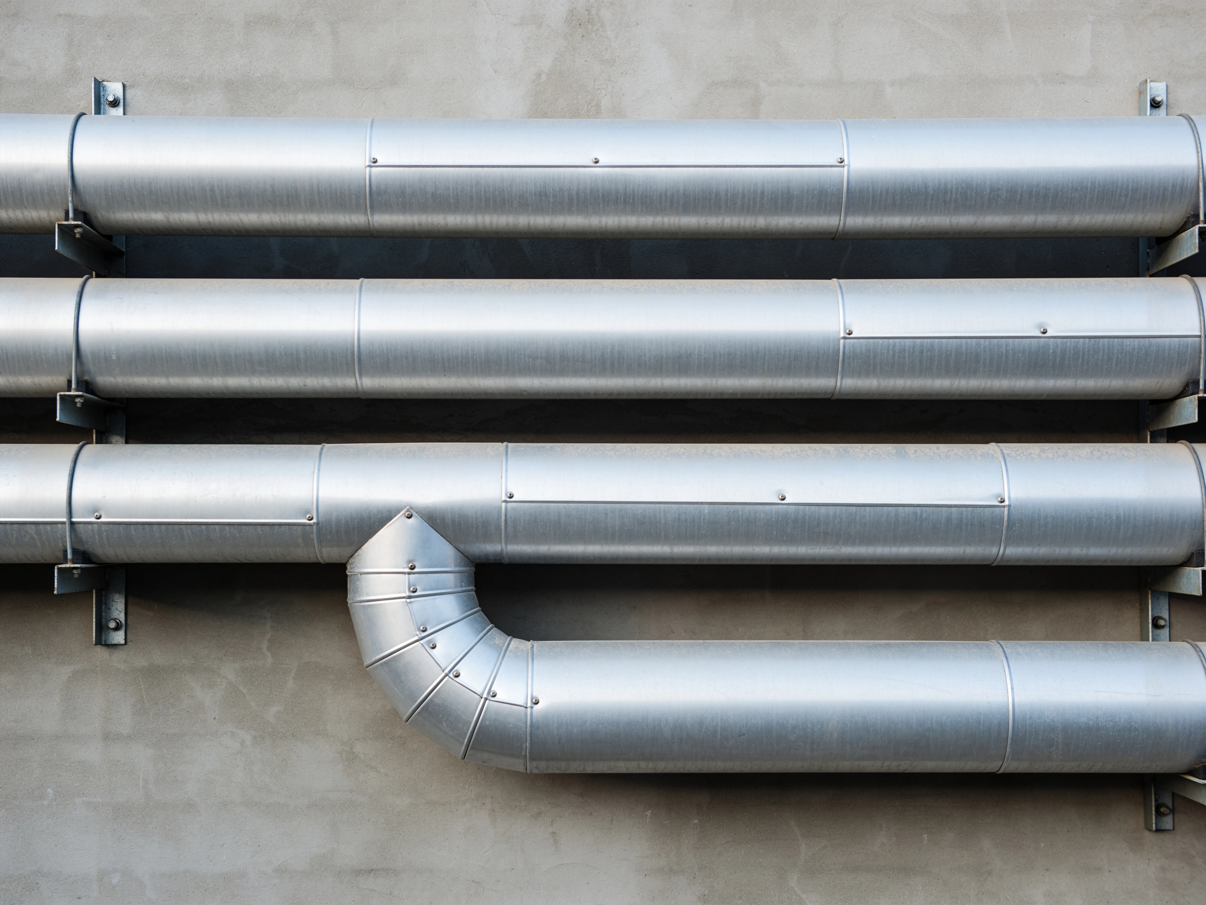 Rohrleitungen mit Ummantelung aus Aluminiumblech an einer Betonwand